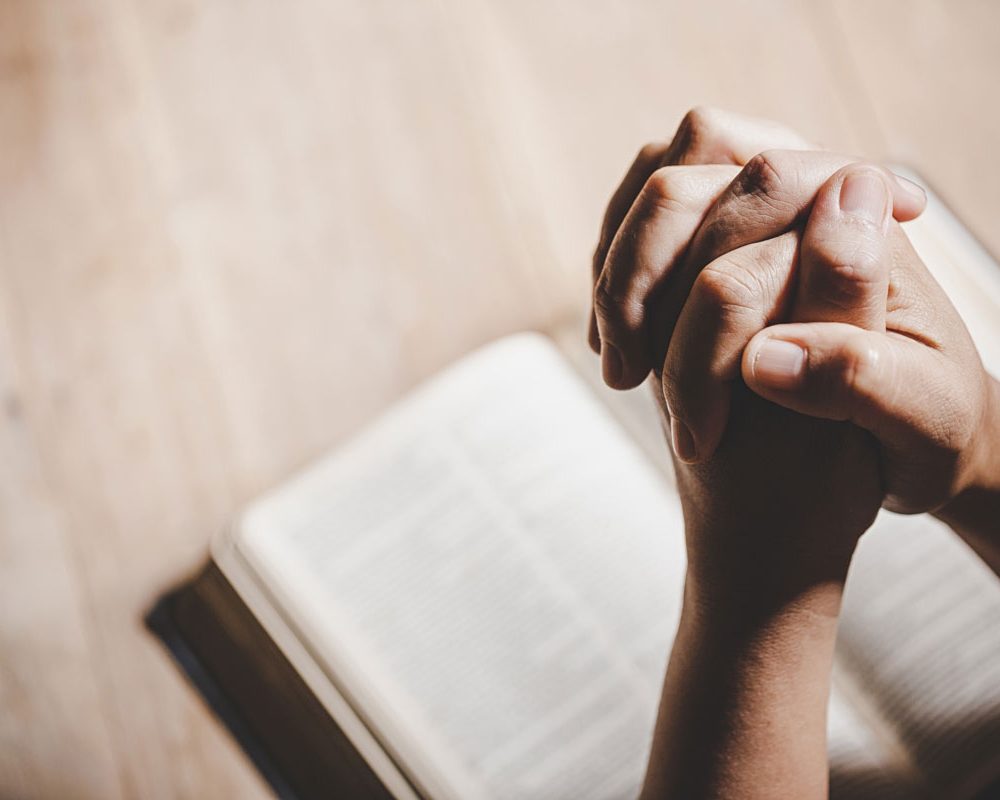 spirituality-and-religion-hands-folded-in-prayer-on-holy-bible-in-church-concept-for-faith